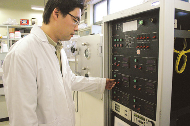 한 연구원이 진공상태에서 금속이나 유기물을 정착시키는 실험기기를 조작하고 있다.